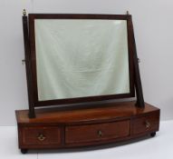 A 19th century mahogany toilet mirror, the rectangular plate between reeded uprights, the bowed