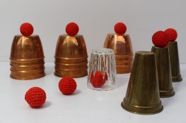 A set of three ribbed copper cups, together with eight balls and three brass cone shaped cups