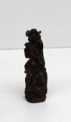 A black forest needle case in the form of a figure and dog seated on a tree trunk, 8cm high