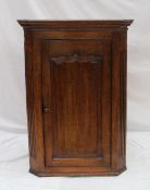 A 19th century oak hanging corner cupboard, the moulded cornice above an ogee moulded panelled