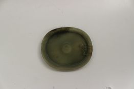 A Chinese jade dish of dished oval form with a raised circular centre, 15 x 12.5cm