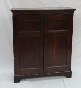 An 18th century oak bookcase with a moulded cornice above a pair of four panelled doors on bracket