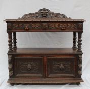A 19th century oak buffet, the shaped back carved with a mask and leaves above a rectangular carved
