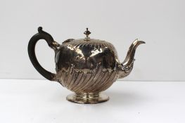 A mid Victorian silver teapot of globe form with a half gadrooned body, on a pedestal foot, London,
