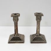 A pair of George V silver candlesticks of column form, with a square form removable sconce, above a
