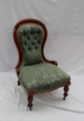 A Victorian mahogany spoon back nursing chair, with button back upholstery and a pad seat on turned