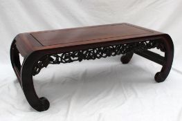 A Chinese hardwood low table of rectangular form, the apron pierced with flower heads and leaves on