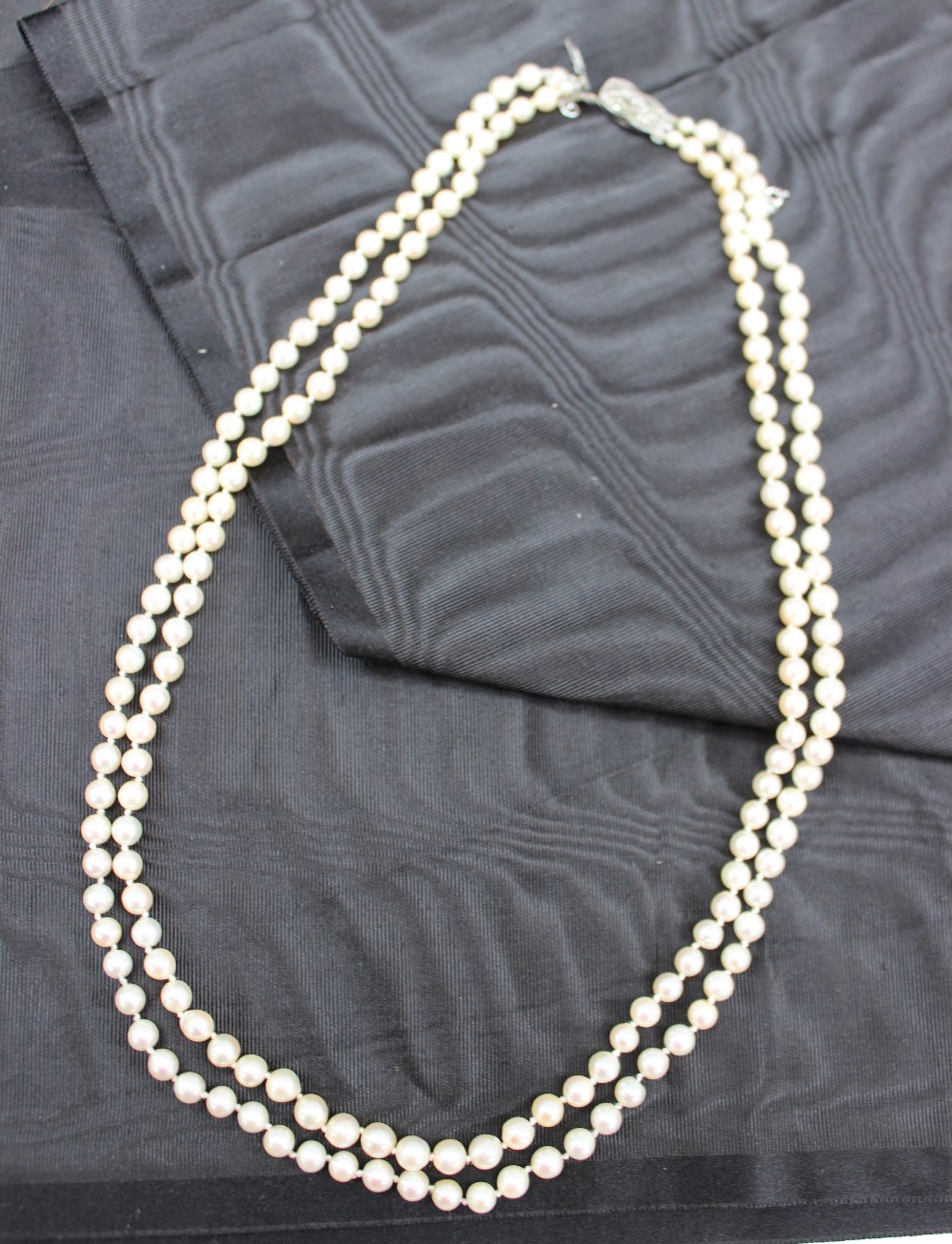 A double strand pearl necklace with graduated pearls to a marcasite clasp marked silver