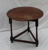 An 18th century oak cricket table, the planked circular top on three gun barrel legs united by