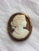A shell cameo brooch of oval form depicting a head and shoulders of a maiden in profile to a yellow