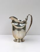 A large white metal jug with a scrolling handle on a pedestal foot, marked Sterling 3 Pints