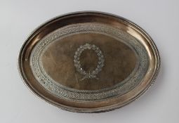 A George III silver teapot stand of oval form with a dot engraved rim, the plate with wreath