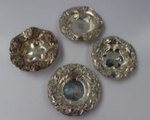 A matched set of four white metal bowls decorated with flower heads and scrolling decoration, all