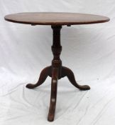 A 19th century oak tripod table, the circular planked top on a snap action, baluster column and