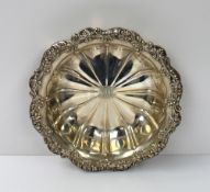 A large white metal dish of circular lobed form, the edge decorated with leaves and flower heads,