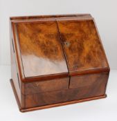A late 19th century walnut stationary cabinet, the sloping front enclosing a fitted interior of