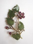 A jade and garnet brooch of floral form to a yellow metal setting