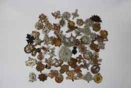 A collections of military cap badges including the Cambridge Regt, Notts & Derby, East Yorkshire,