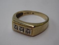 A three stone ring the brilliant cut stones to a white metal setting and 15ct yellow gold shank,