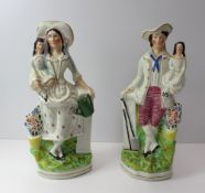 A pair of Staffordshire flat back figures both holding children, 29.5 cm high