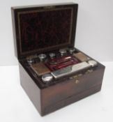 A Victorian rosewood travelling box of rectangular form fitted with electroplated and glass bottles,