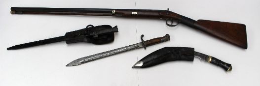 A percussion cap shotgun, together with two bayonets and a Gurkha knife.