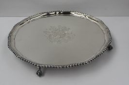 An Elizabeth II silver salver of circular form with a shaped gadrooned edge, engraved with a coat of
