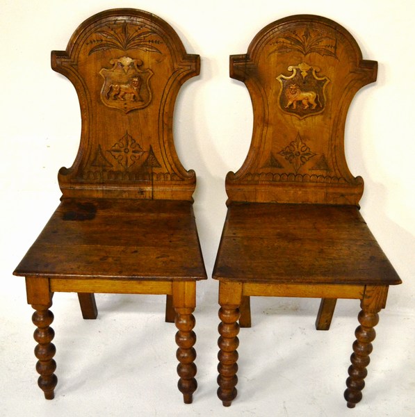 A PAIR OF EARLY 19TH CENTURY ENGLISH OAK HALL CHAIRS the shield backs mounted with cartouche’s, each