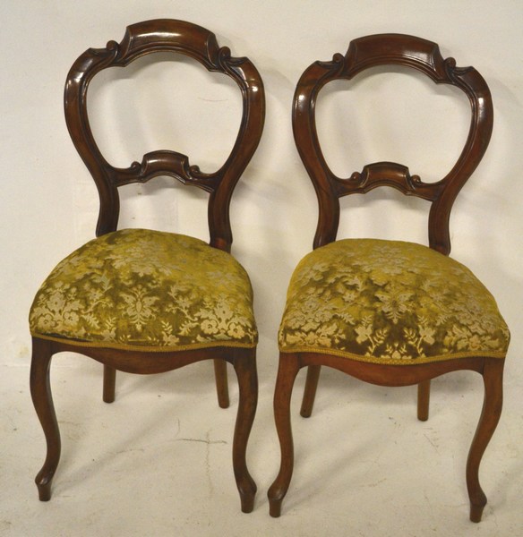 A PAIR OF VICTORIAN WALNUT BUSTLE BACK DINING CHAIRS the backs with rails carved in stylized foliage