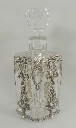 A Continental cut glass scent bottle and stopper with silver casing, cast with foliage, ribbon