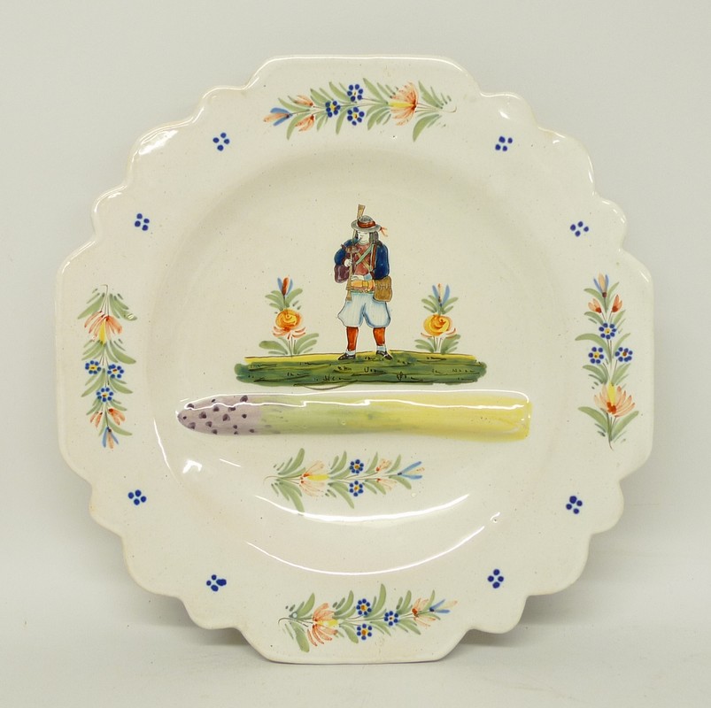 A Quimper pottery asparagus plate moulded with asparagus and painted with a musician and flowers, HB