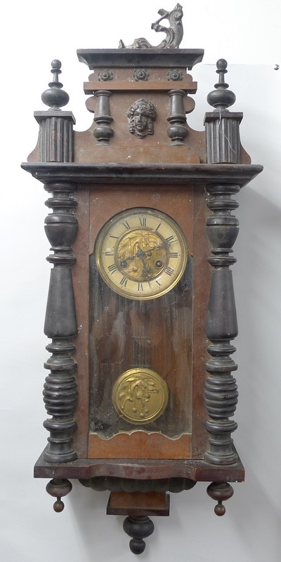 A Vienna wall clock, with turned wood pilasters, the brass centre to the face and the pendulum