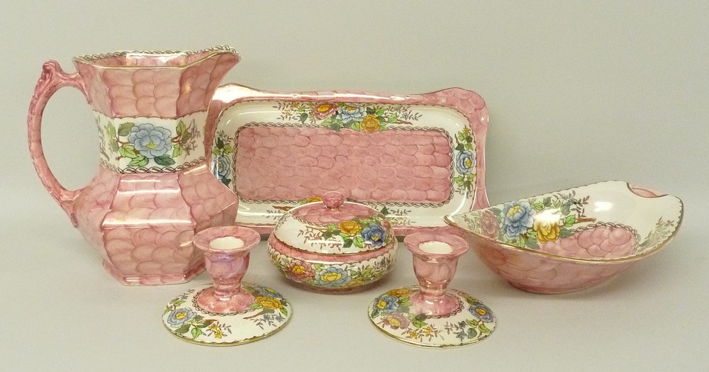 A quantity of Maling lustre pottery decorated in the Peony Rose pattern against a pink scale ground,