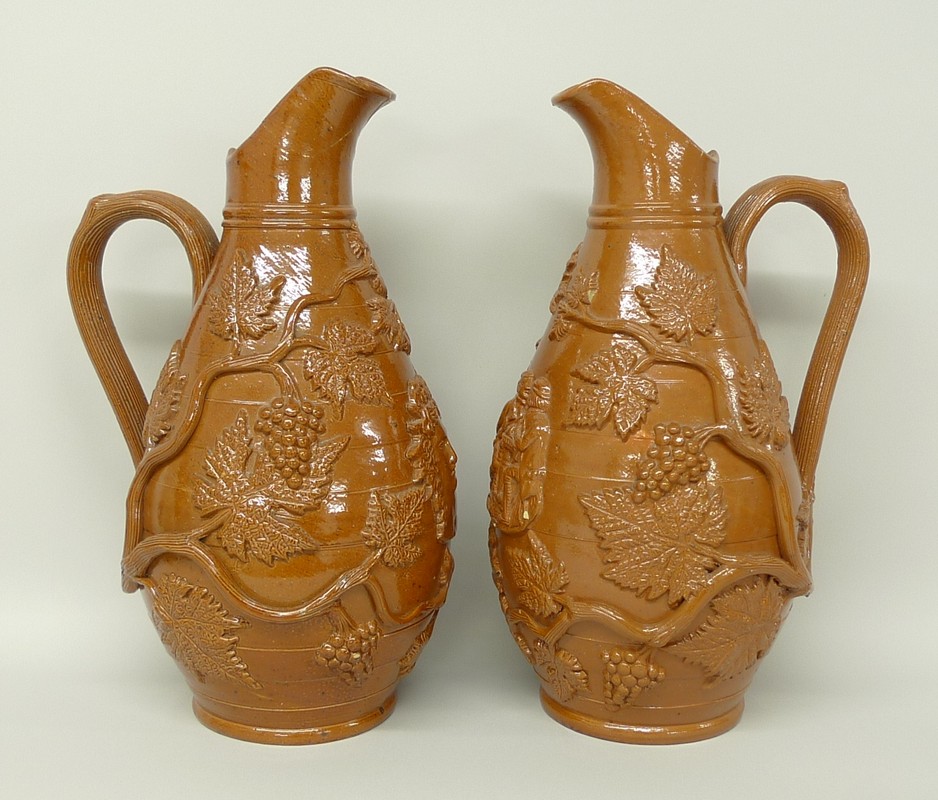 A pair of stoneware harvest jugs, mid 19th century, with raised vine leaf decoration, one with the