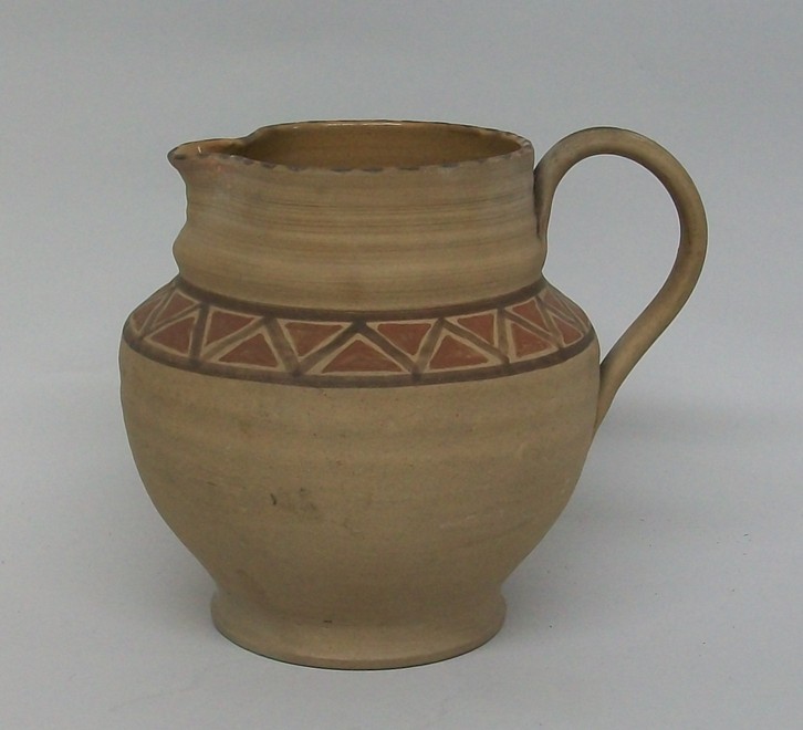 A Poole brown matt unglazed jug, circa 1920, with ribbed decoration and painted to the shoulder in