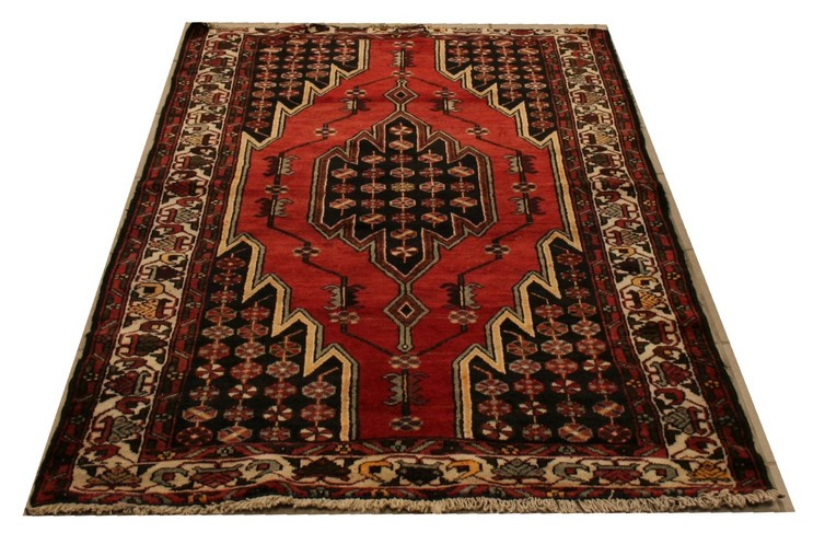 A Hamadan rug with brick red ground over large black jagged edged corners filled with multiple