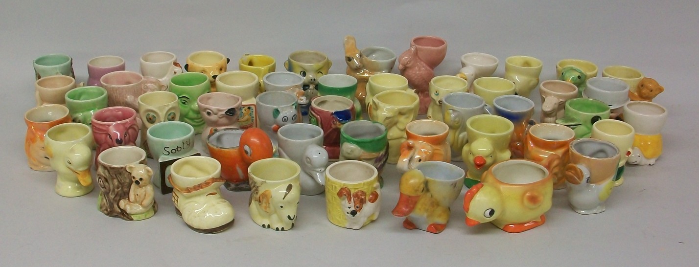 A collection of porcelain and pottery egg cups, 1920s onwards, many modelled as animals and