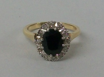 A 9ct gold and sapphire ring, oval set in a surround of diamonds, size M, 3.9g.