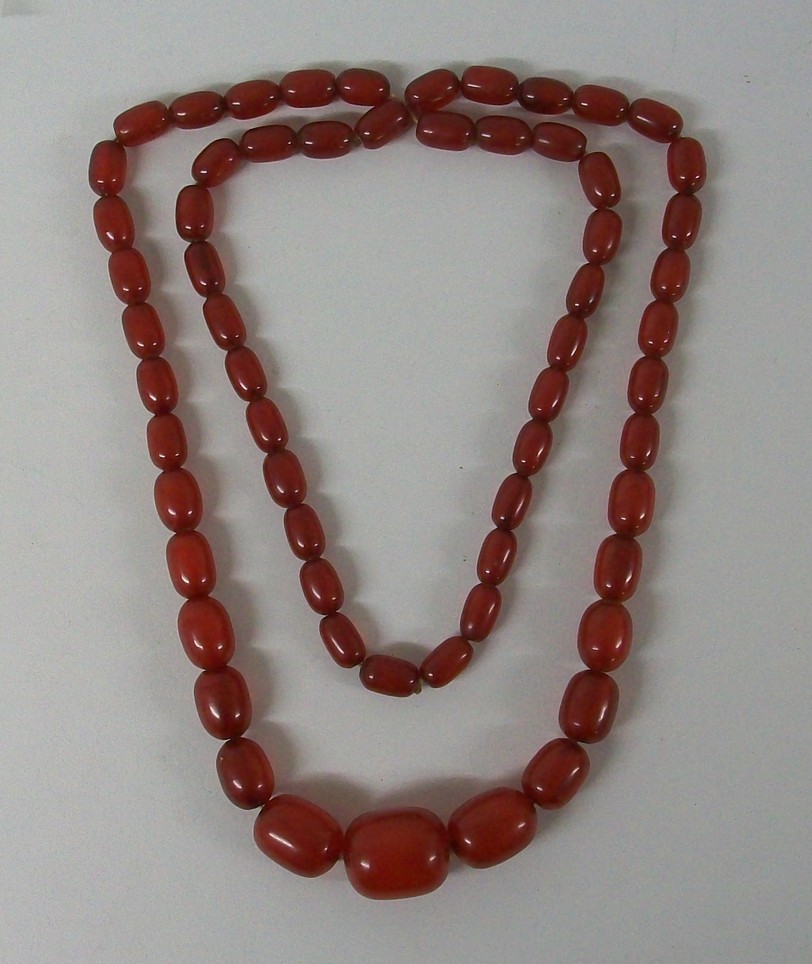 A string of graduated red amber beads, 98cm.