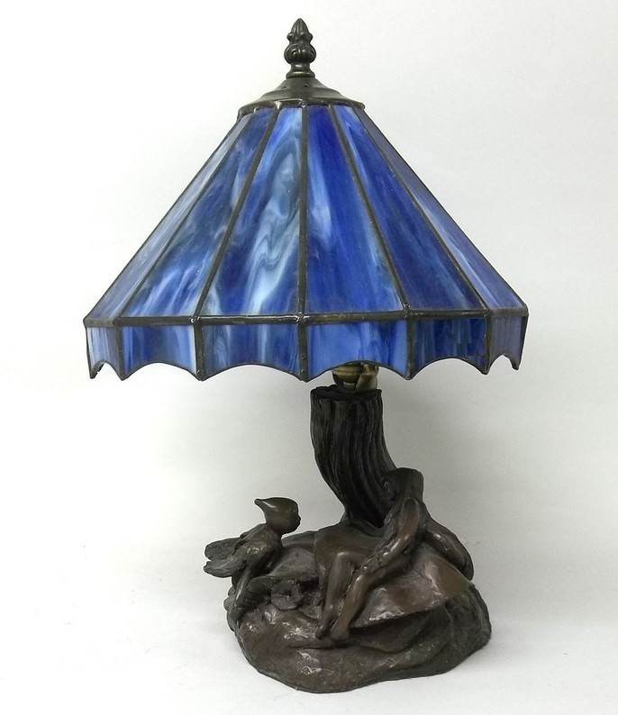 A bronze bedroom table lamp with gnarled and twisted tree stem, with fairy and elf below a blue