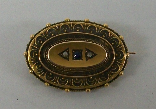 A Victorian 15ct gold oval hair locket brooch set centrally with a sapphire flanked by two old cut