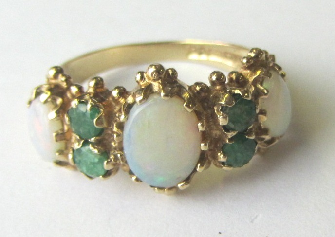 A 9ct gold, opal and emerald set ring, mounted with three oval opals and with two pairs of
