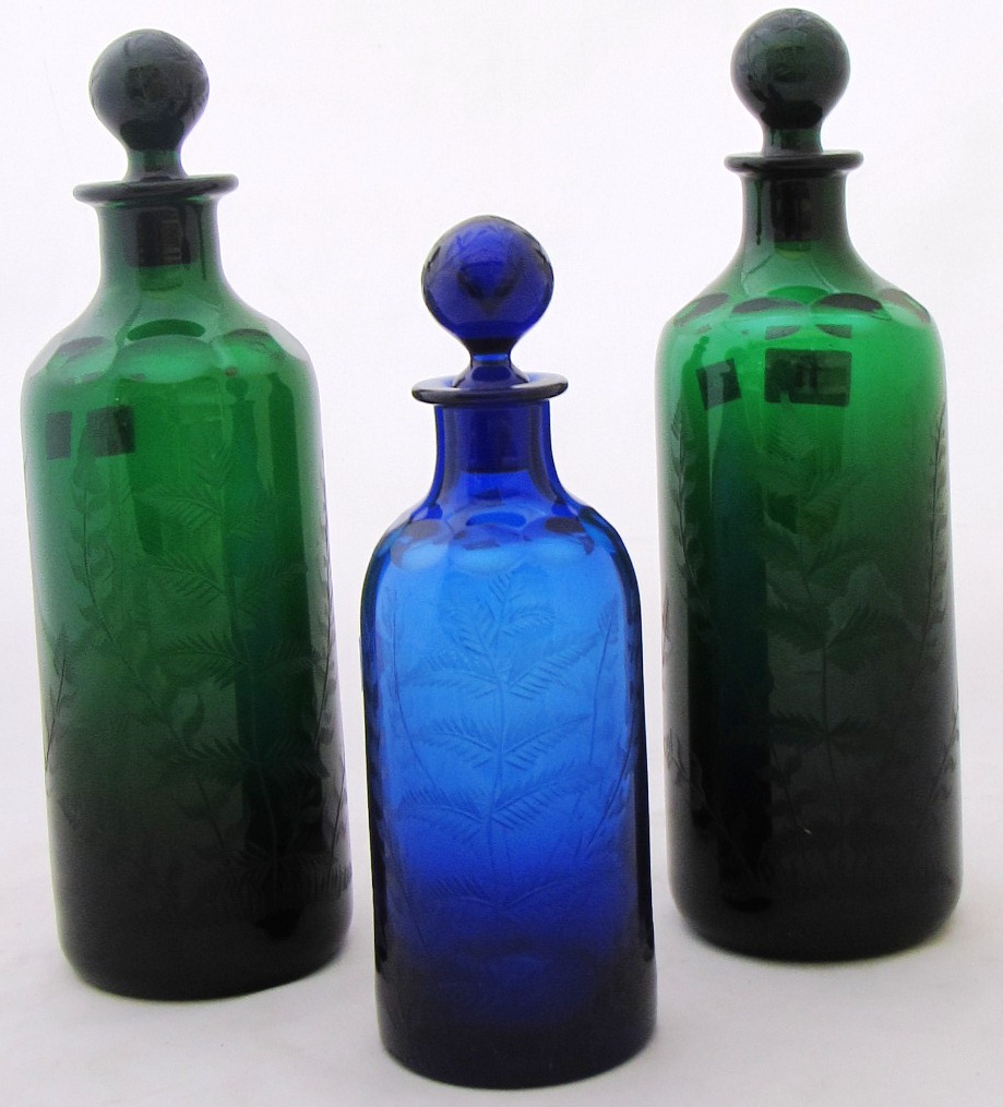 Two green glass decanters and stoppers by William Yeoward, engraved with ferns, 30cm., and a smaller