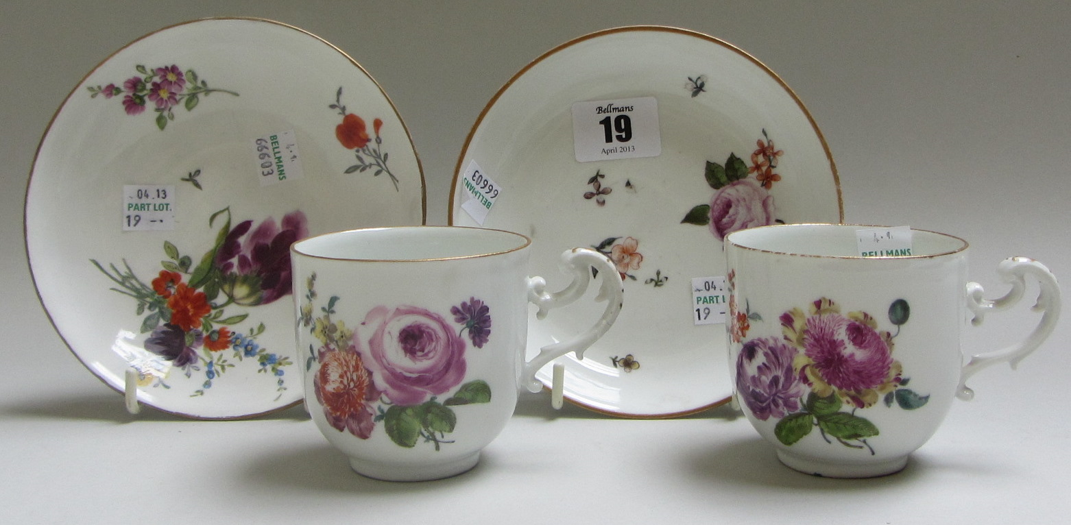 A pair of Meissen cups and saucers, circa 1760, painted with flower sprays, blue crossed swords