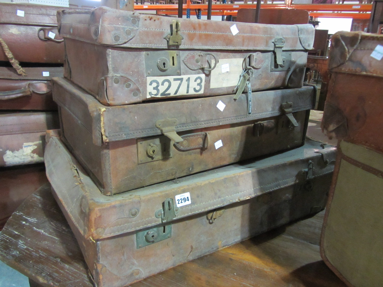 Three various brown leather suitcases, one with a key.