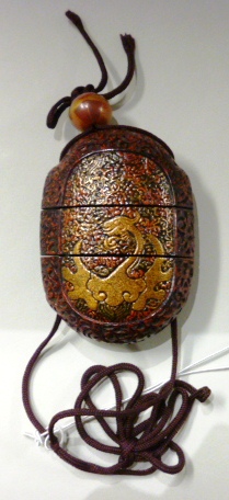 A Japanese red lacquer two-case inro, Edo period, carved with scrollwork, each side gilt with a