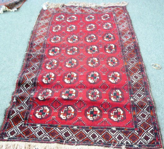 An Indian Bokhara rug, the madder field with four columns of eight guls and a diamond border, 180