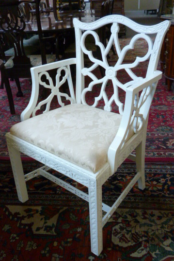 A set of eight white painted dining chairs with blind fret decoration, including two carvers.