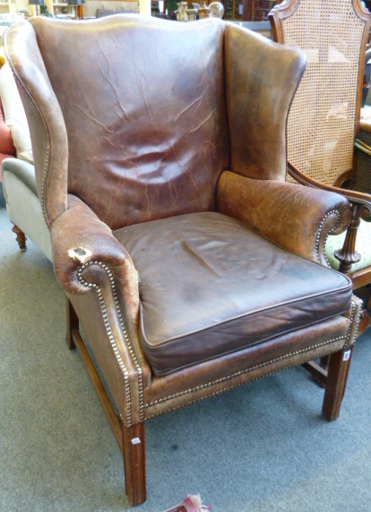 An 18th century design wingback armchair with studded brown leather upholstery