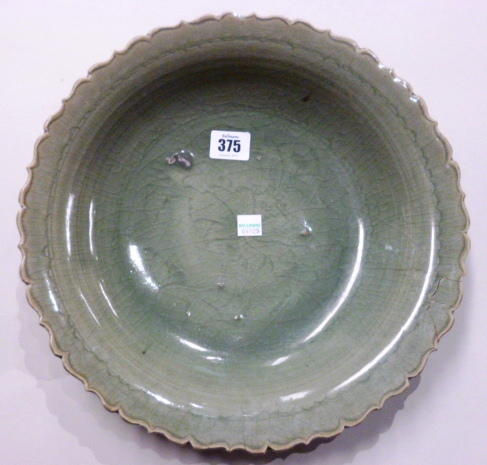A Chinese celadon dish, late Ming dynasty, the shallow bowl with a cusped rim, the centre incised